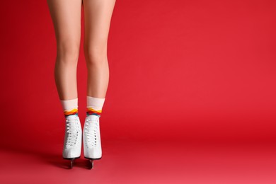 Photo of Woman in elegant white ice skates on red background, closeup of legs. Space for text