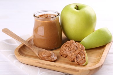 Photo of Fresh green apples with peanut butter on white wooden table