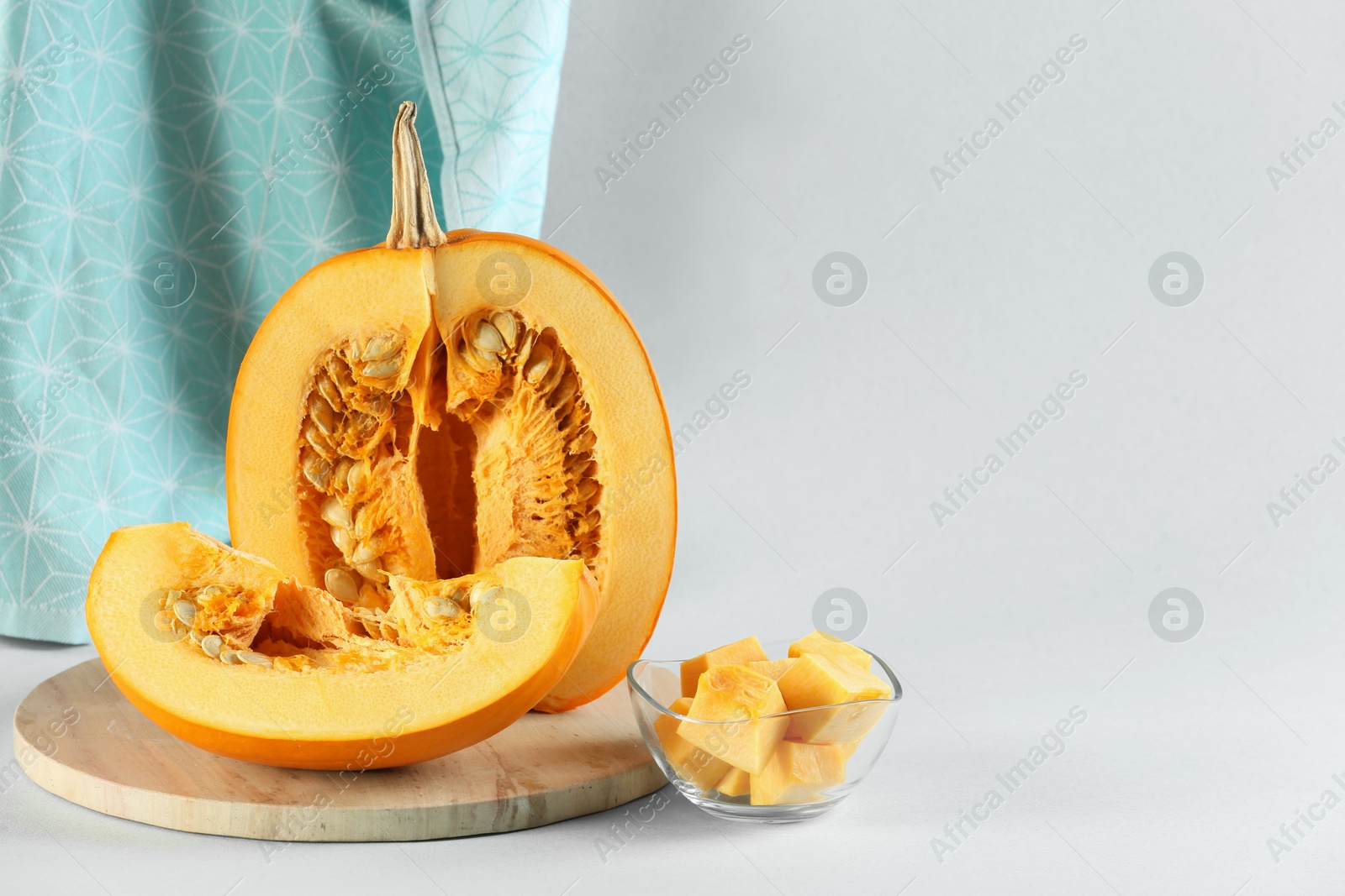 Photo of Cut fresh ripe pumpkin on light blue background, space for text