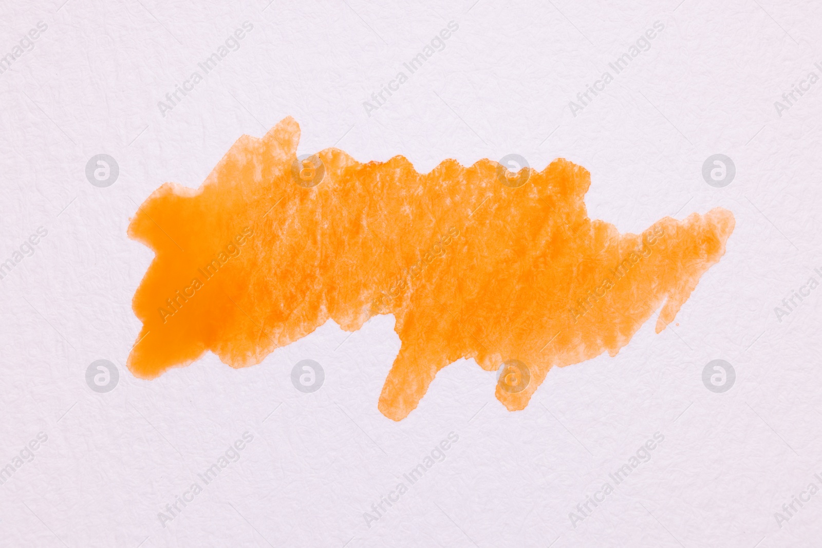 Photo of Blot of orange watercolor paint on white paper, top view