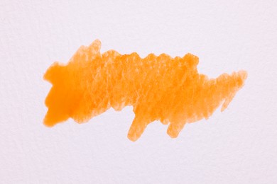 Photo of Blot of orange watercolor paint on white paper, top view