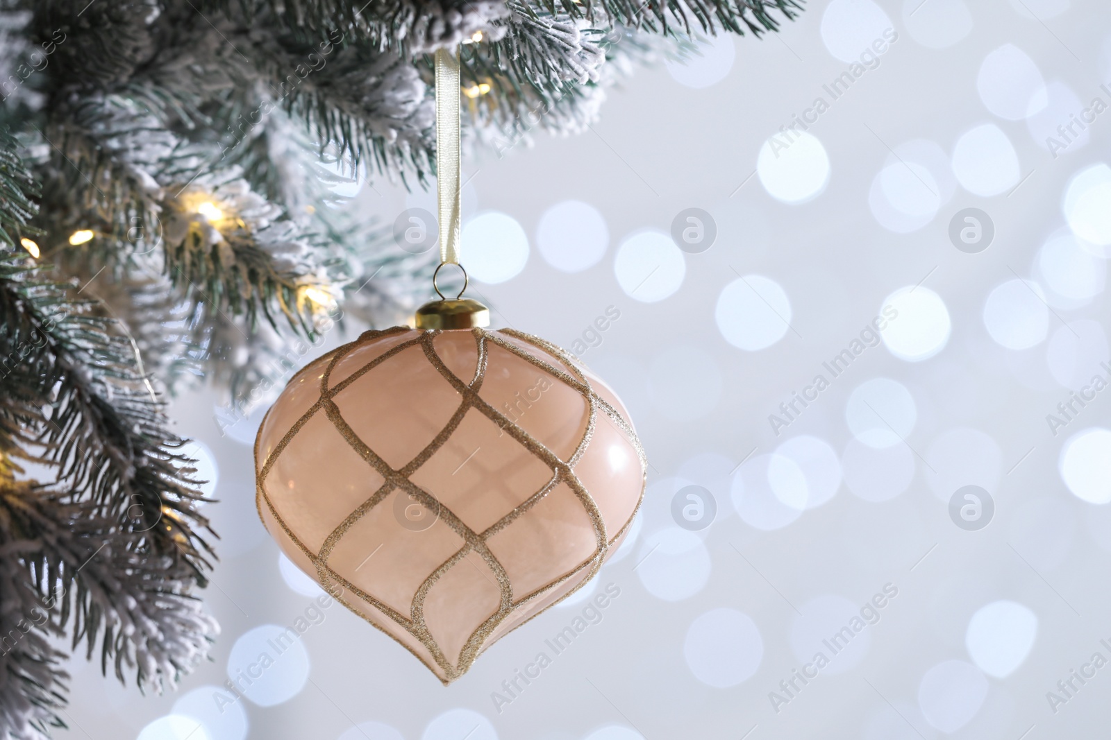 Photo of Christmas tree decorated with holiday bauble against blurred lights, closeup