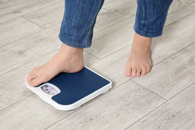 Photo of Overweight woman using scales indoors