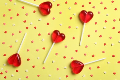 Photo of Sweet heart shaped lollipops and sprinkles on yellow background, flat lay. Valentine's day celebration