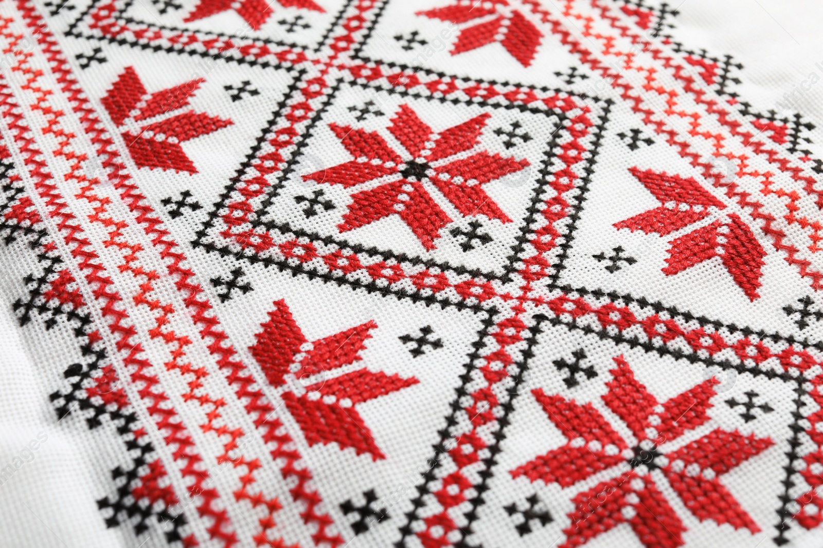 Photo of Traditional Ukrainian embroidery on white canvas as background, closeup. National handicraft