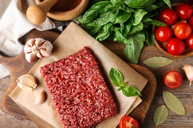 Photo of Flat lay composition with fresh raw minced meat on wooden table