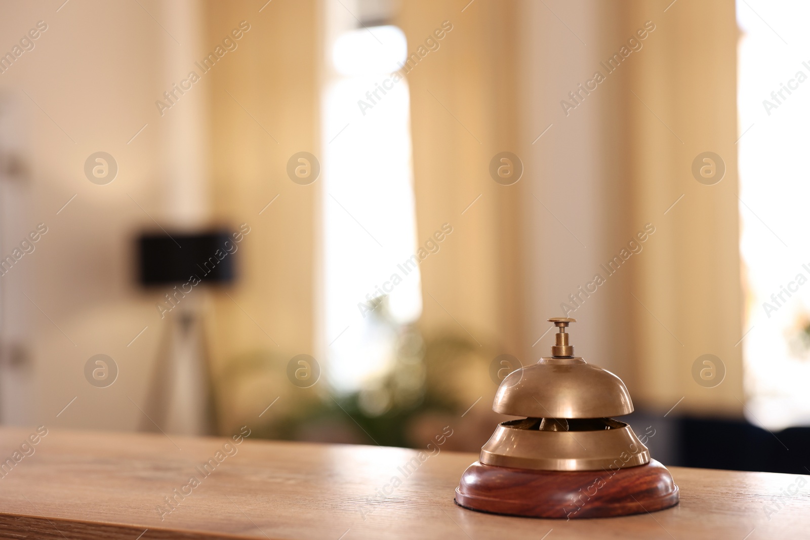 Photo of Hotel service bell on wooden reception desk. Space for text