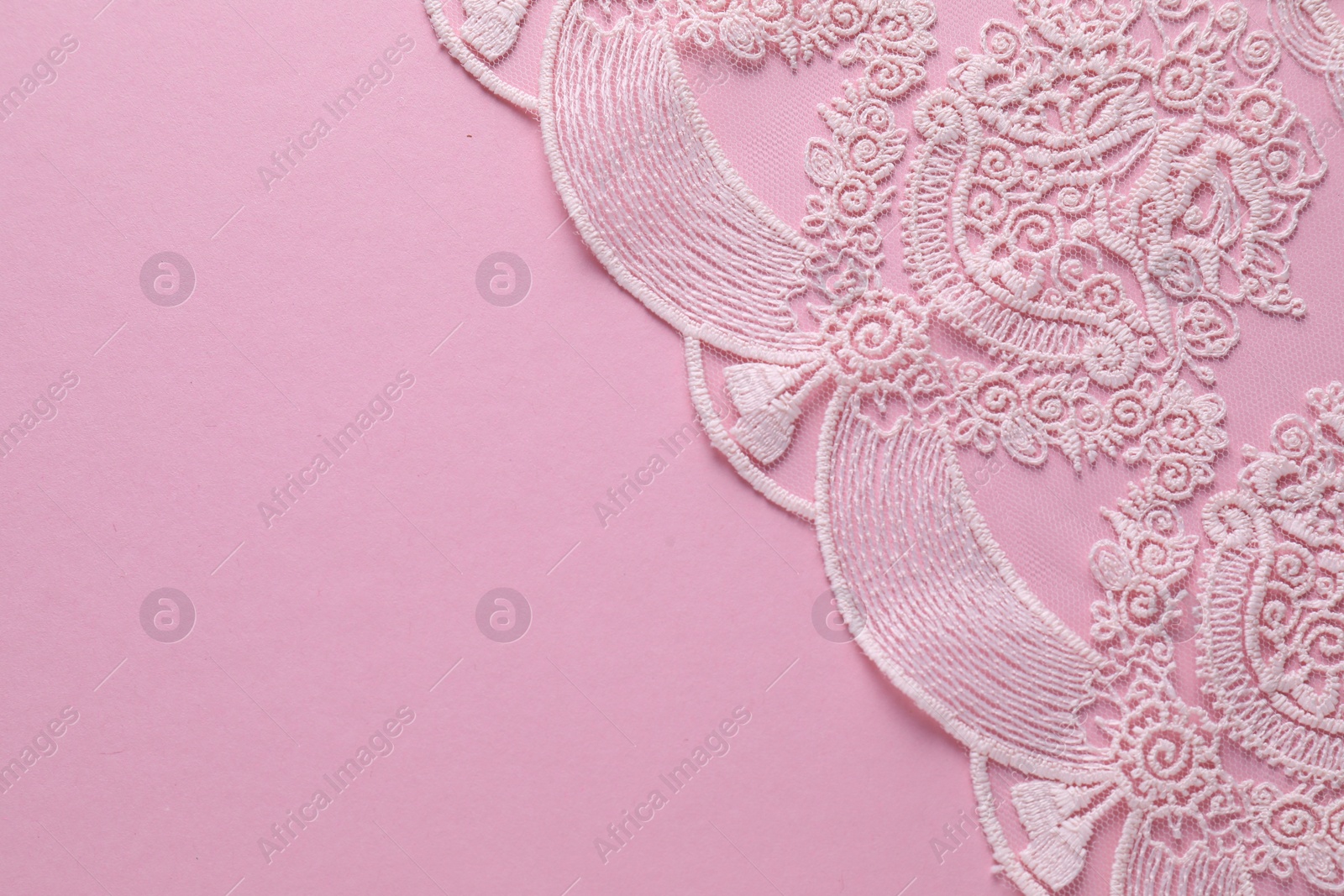 Photo of White lace on pink background, top view. Space for text