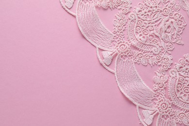 Photo of White lace on pink background, top view. Space for text