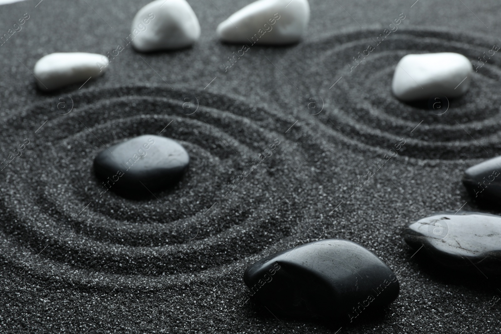 Photo of Stones on black sand with beautiful pattern. Zen and harmony