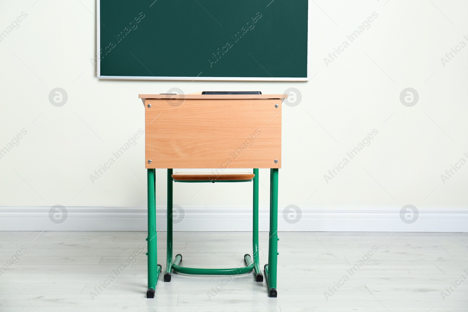 Photo of Modern empty school desk near chalkboard in classroom