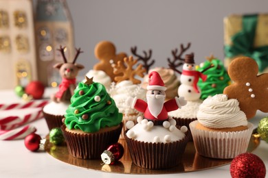 Photo of Different beautiful Christmas cupcakes and baubles on white table