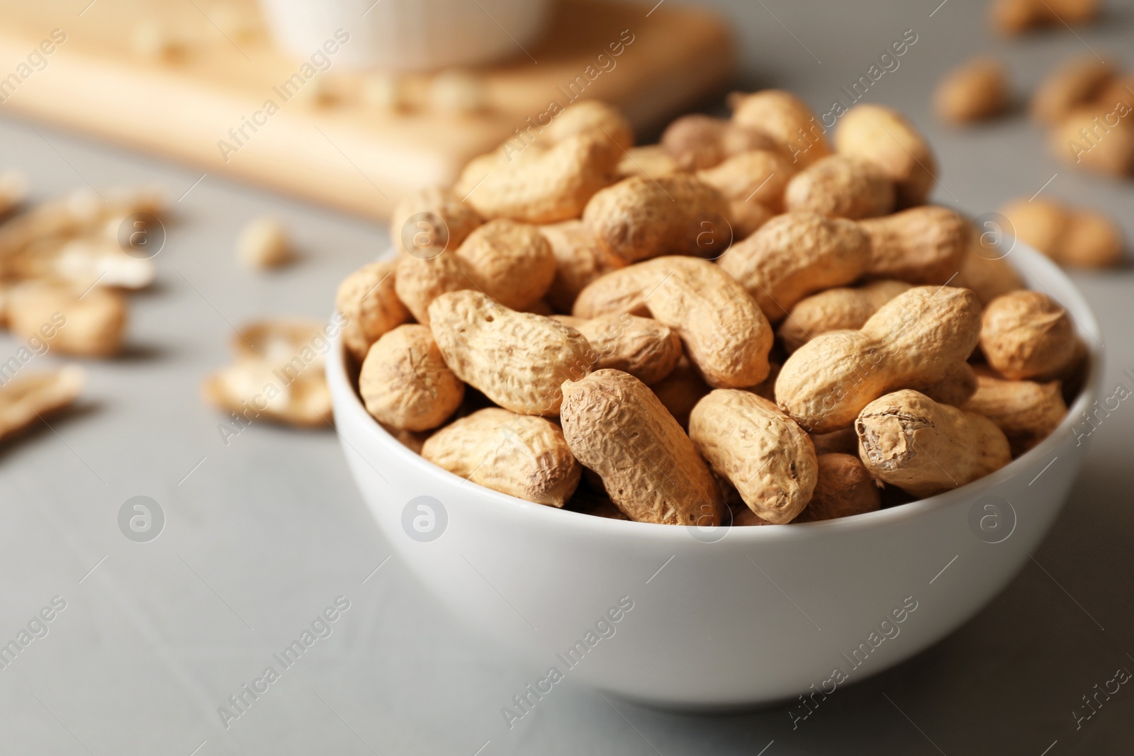 Photo of Bowl with peanuts in shell on table