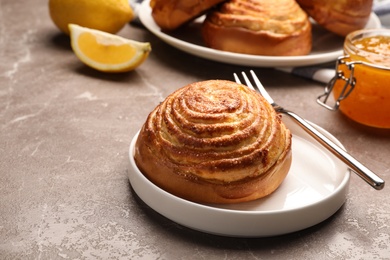 Photo of Plate with tasty bun on stone table, space for text. Fresh from oven