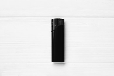 Stylish small pocket lighter on white wooden background, top view