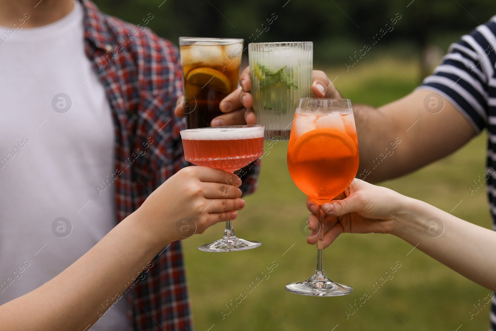 Photo of Friends clinking glasses with cocktails outdoors, closeup