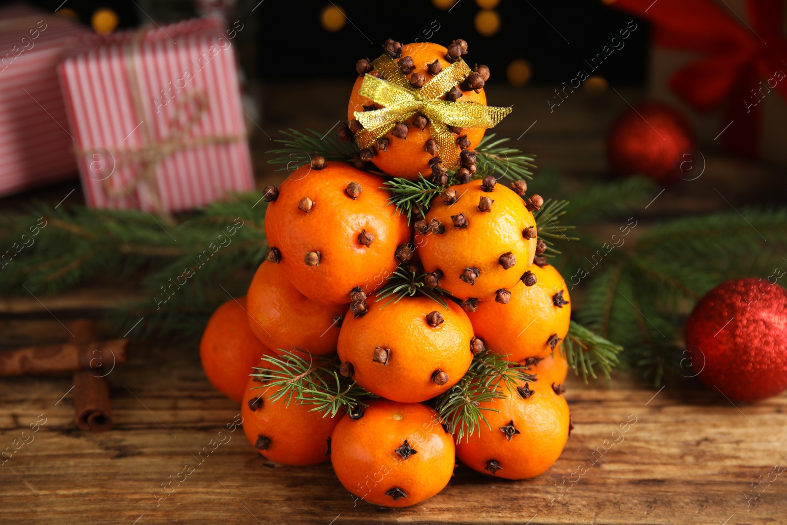 Photo of Pomander balls made of tangerines with cloves and fir branches on wooden table