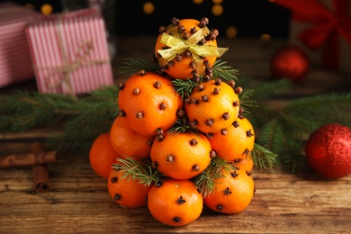 Pomander balls made of tangerines with cloves and fir branches on wooden table