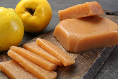Photo of Tasty sweet quince paste and fresh fruits on grey table, closeup