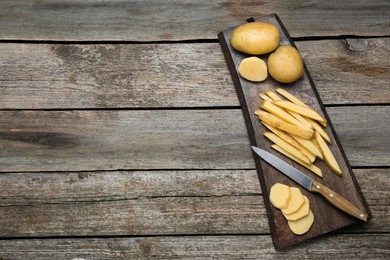 Photo of Potatoes and knife on wooden table, top view with space for text. Cooking delicious french fries