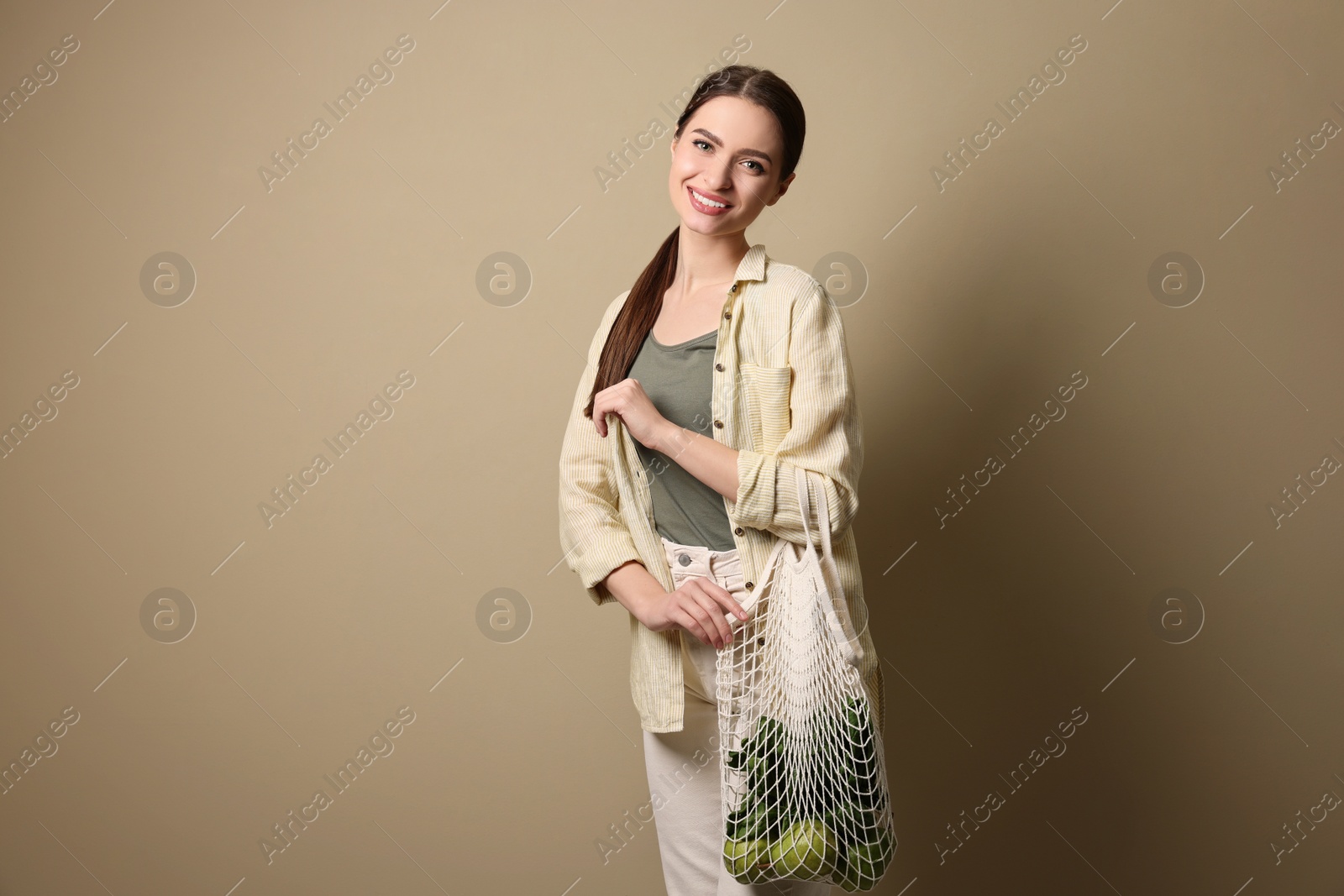 Photo of Woman with eco bag full of products on beige background, space for text