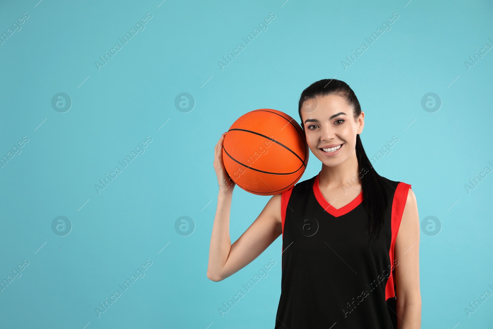 Photo of Basketball player with ball on light blue background. Space for text