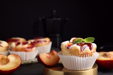 Delicious cupcakes with plums on black table, closeup