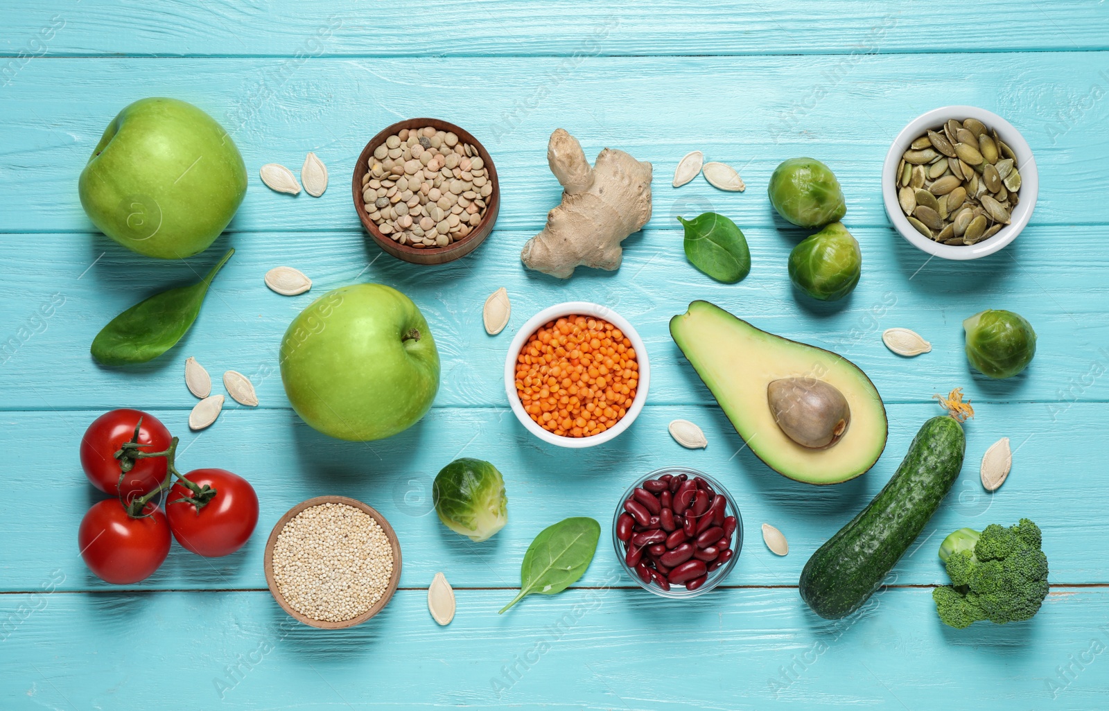 Photo of Fresh vegetables, fruits and seeds on light blue wooden table, flat lay