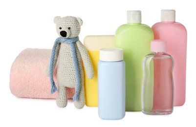 Photo of Bottles of baby cosmetic products, towel and toy bear on white background
