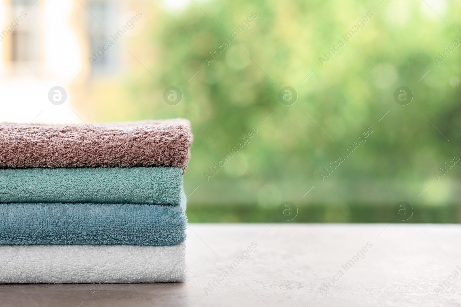 Photo of Stack of clean towels on table against blurred background. Space for text