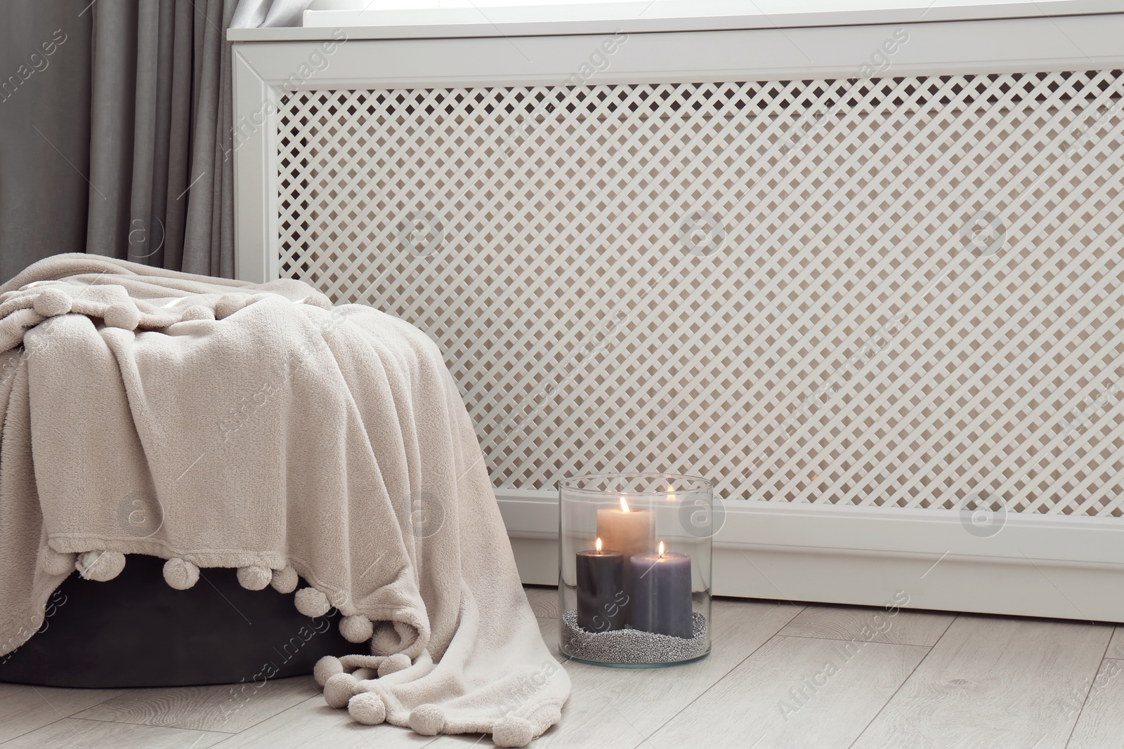 Photo of Glass vase with burning candles on floor indoors