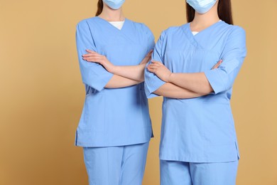 Photo of Nurses wearing medical uniforms on light brown background, closeup