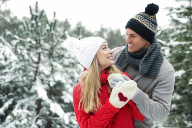 Beautiful happy couple in snowy forest on winter day