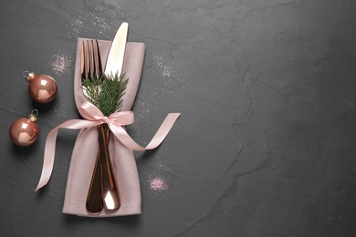 Cutlery set on black table, top view with space for text. Christmas celebration