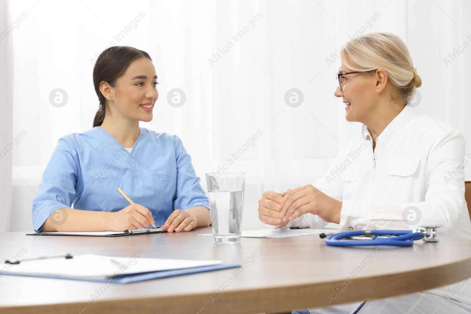 Photo of Medical conference. Doctors having discussion at wooden table in office