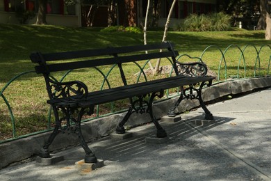 Beautiful old black bench near pathway in park