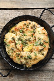 Photo of Delicious chicken piccata with herbs on wooden table, top view