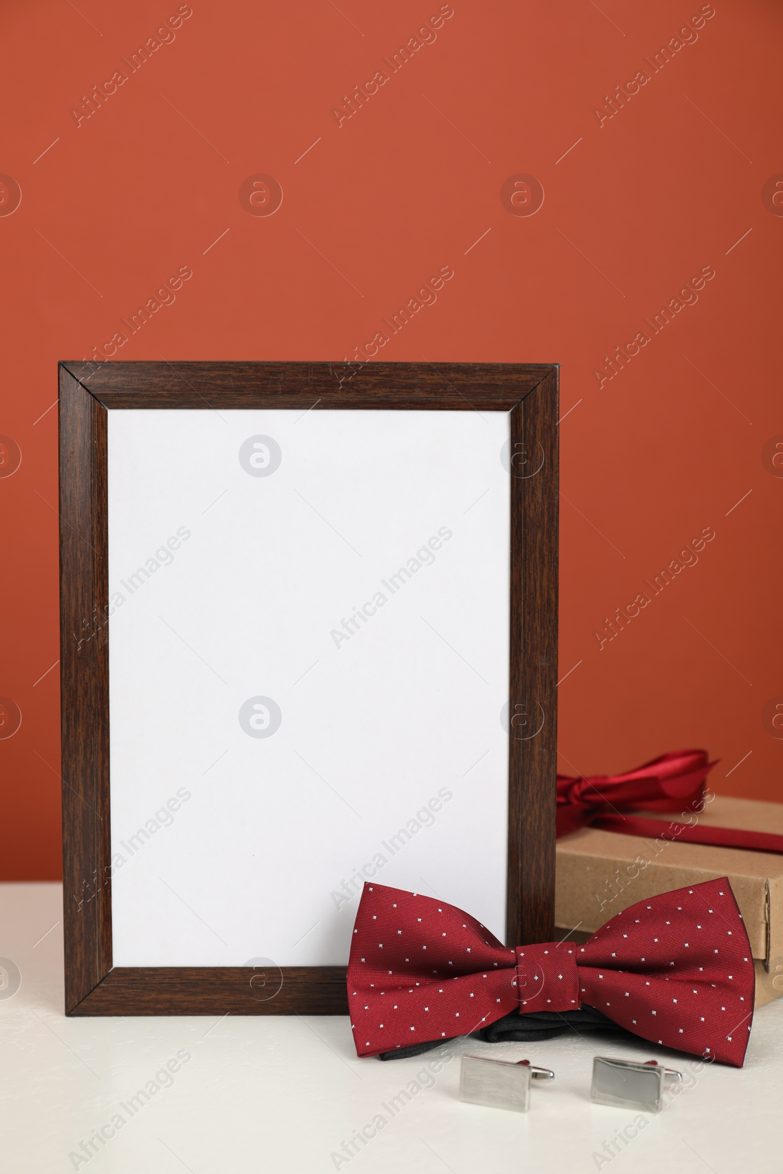 Photo of Happy Father's Day. Empty frame, bow tie, cufflinks and gift box on white table. Space for text