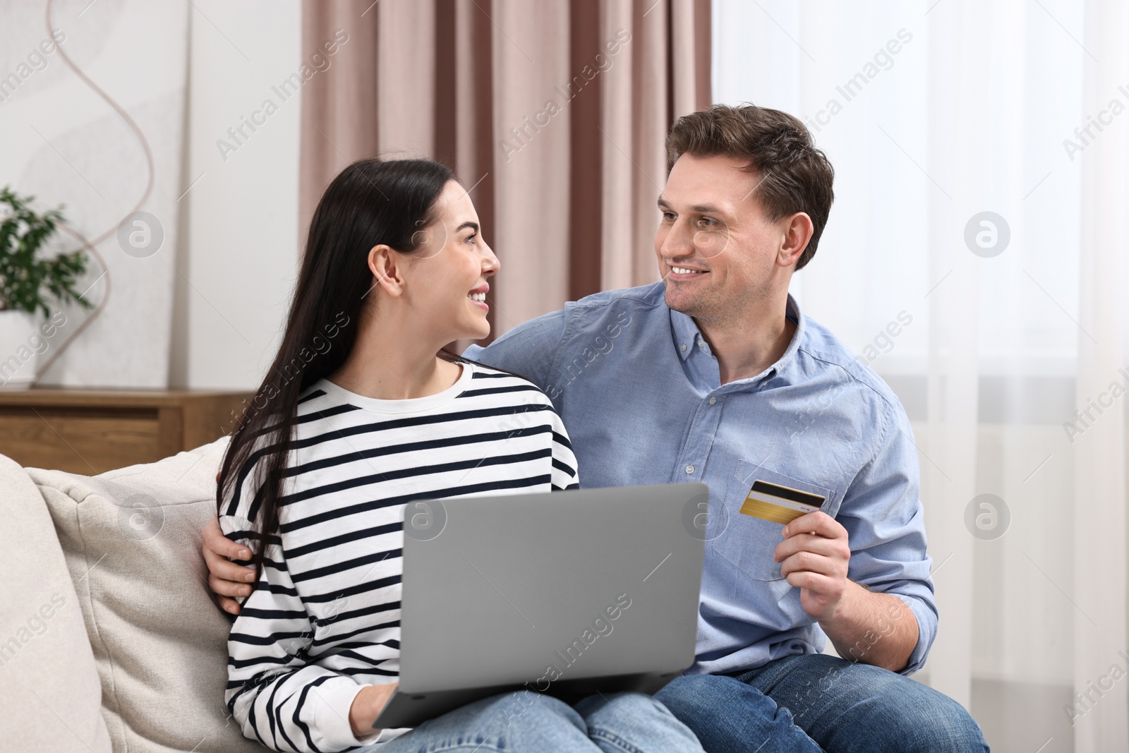 Photo of Happy couple with laptop and credit card shopping online together at home