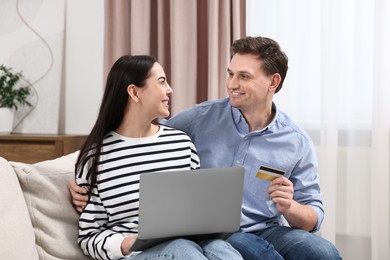 Happy couple with laptop and credit card shopping online together at home