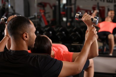 Young woman working out with professional trainer in modern gym