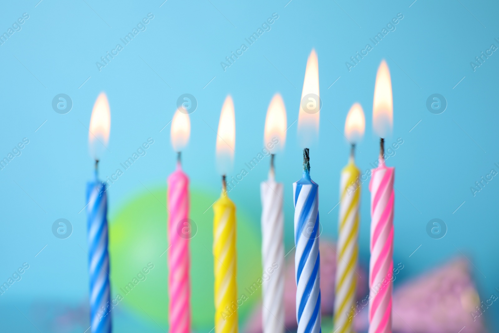 Photo of Burning birthday cake candles on color background