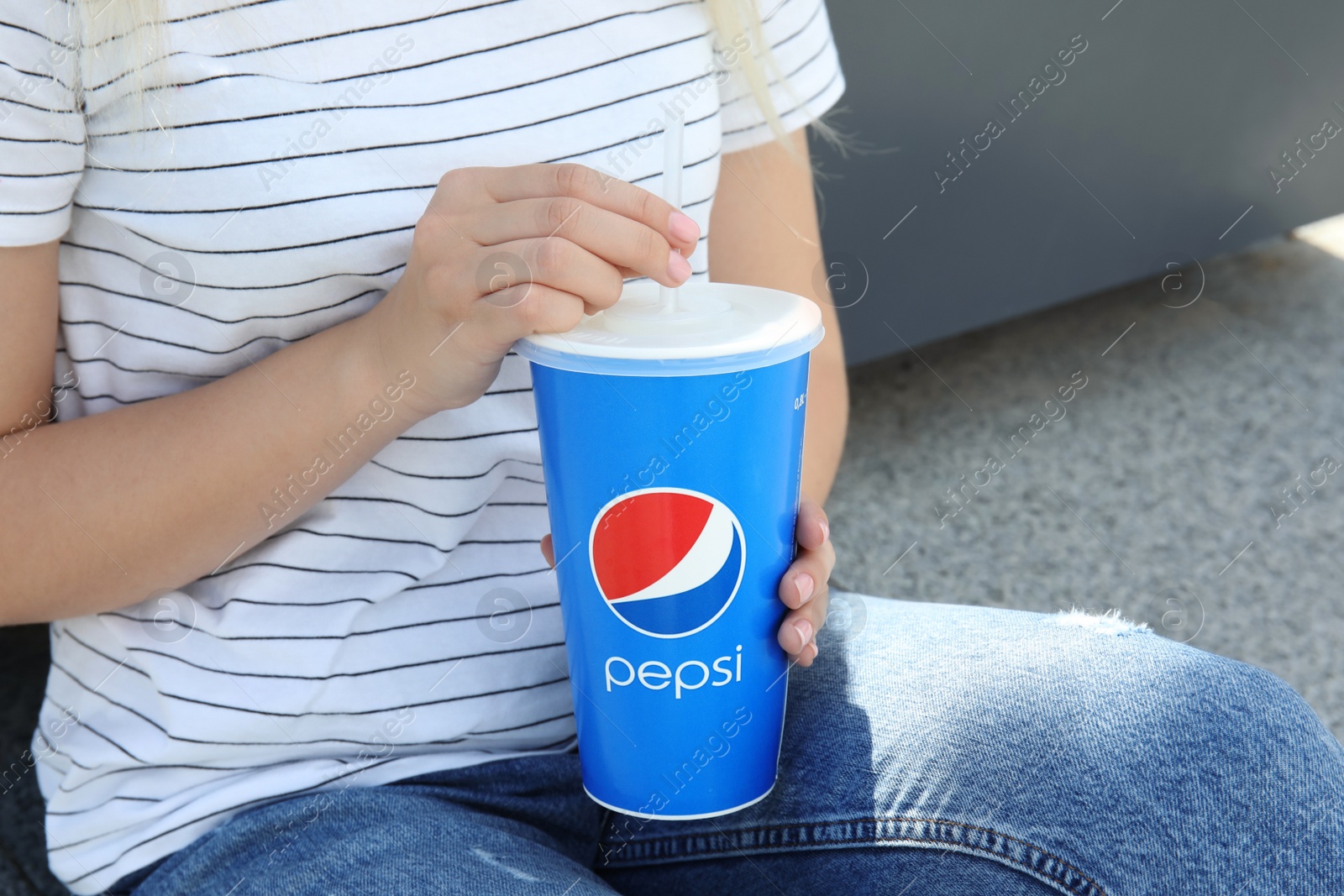 Photo of MYKOLAIV, UKRAINE - JUNE 9, 2021: Woman with paper Pepsi cup outdoors, closeup