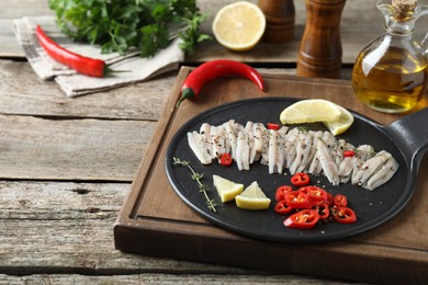 Photo of Tasty anchovies with spices and lemon slices on wooden table. Space for text