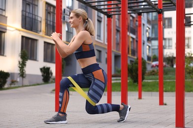 Photo of Athletic woman doing exercise with fitness elastic band at outdoor gym