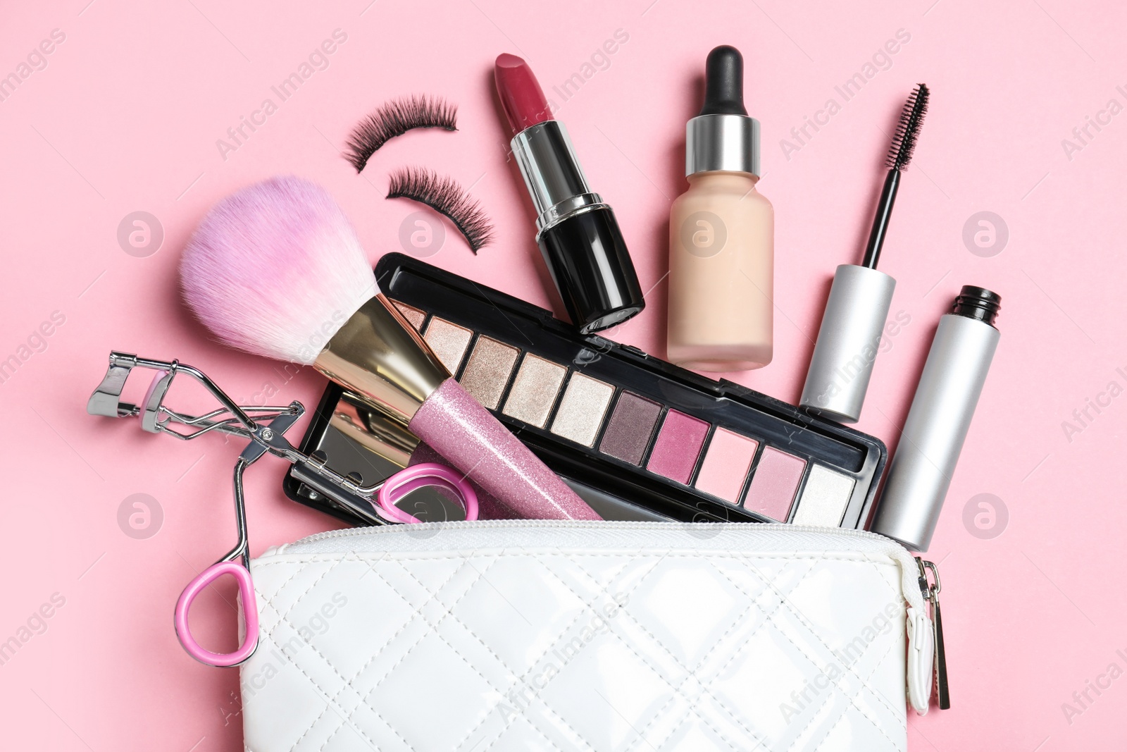 Photo of Cosmetic bag and makeup products with accessories on pink background, flat lay