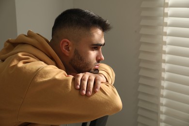 Photo of Sad young man at home. Space for text