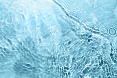 Rippled surface of clear water on light blue background, top view