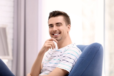 Photo of Young man sitting in armchair at home