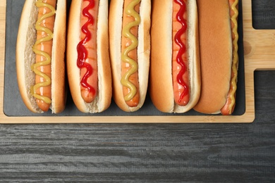 Board with hot dogs on wooden table, top view